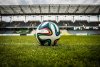 A football lying on the grass of a football pitch in a stadium